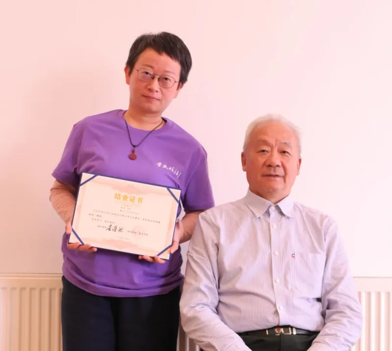 Emma with Master Li Daozheng, founder of the Li Shi Bian Method, holding her completion certificate