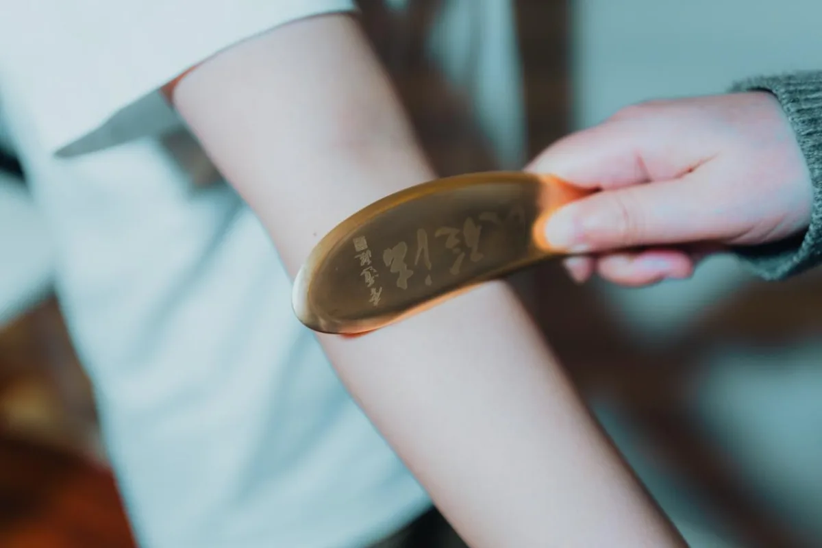 Professional gua sha treatment technique using copper bian tool on arm